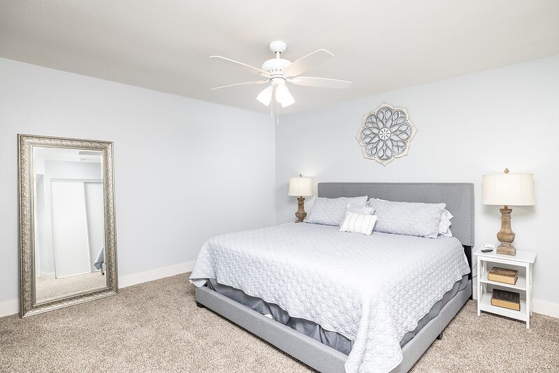 Bedroom with a king bed, upholstered headboard, and a leaning floor mirror