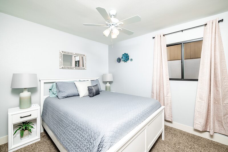 Bedroom with a queen bed, white headboard, and matching nightstand lamps