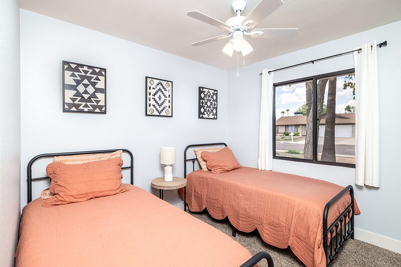 Bedroom with two black framed twin beds and coral bedding