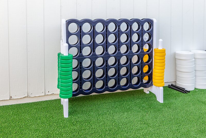 Giant Connect Four game standing on turf against a white wall