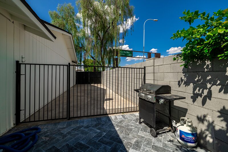 Gas grill on the side patio behind a gated entry