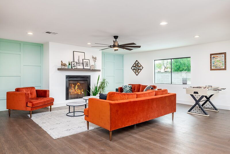 Open living room with rust colored sofas, a fireplace, and a foosball table