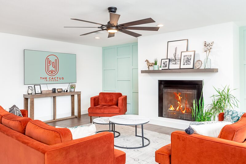 Living room seating facing the large wall mounted TV beside a lit fireplace