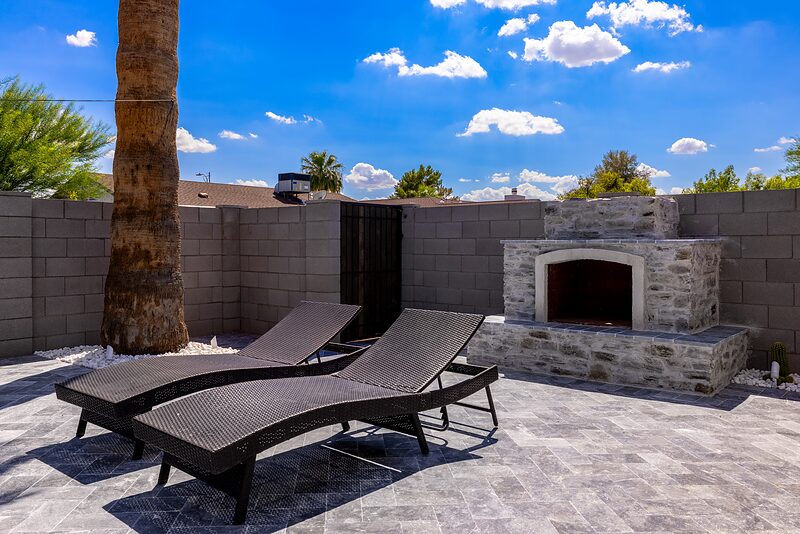 Two loungers beside a stone outdoor fireplace on the pool deck
